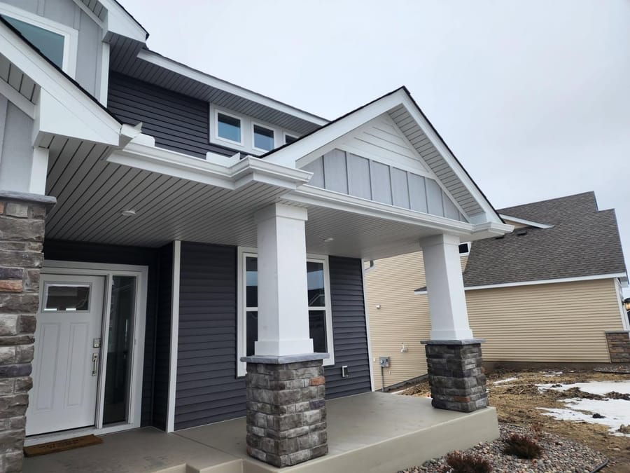 Close-up view of custom white gutters seamlessly installed along the angled roofline of a front porch in Lino Lakes, MN.