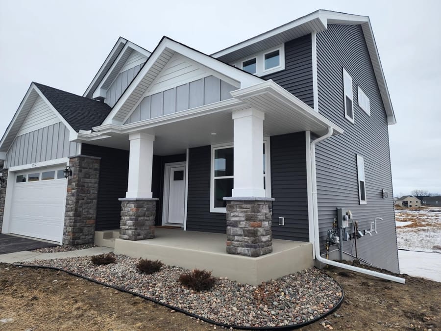 Dark gray house in Lino Lakes MN featuring custom-fitted white seamless gutters and downspouts by Ultimate Gutter Solutions.